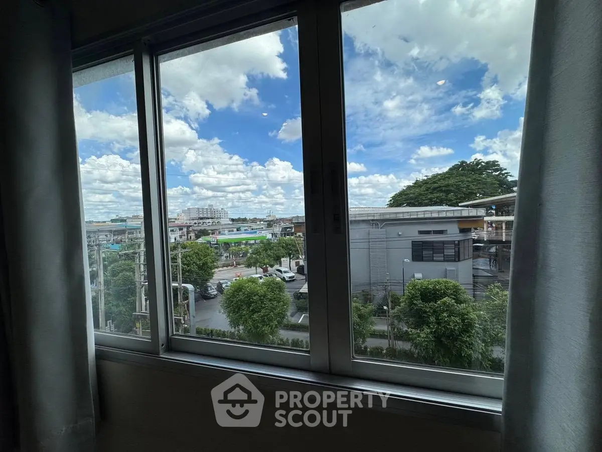 Stunning urban view from a modern apartment window, showcasing cityscape and lush greenery.