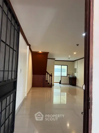 Spacious open-plan living area with modern kitchen and staircase, perfect for family gatherings.