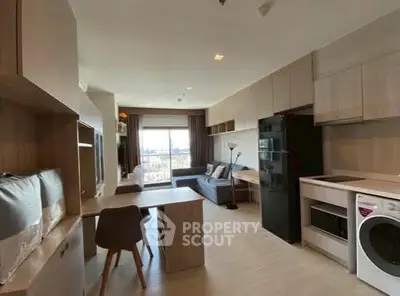 Modern open-plan living room with kitchen and washing machine, featuring sleek furniture and large window view.
