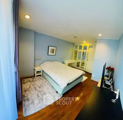 Spacious bedroom with modern decor and wooden flooring in a cozy apartment.