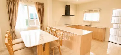 Spacious kitchen with dining area featuring modern wooden cabinetry and marble countertops.