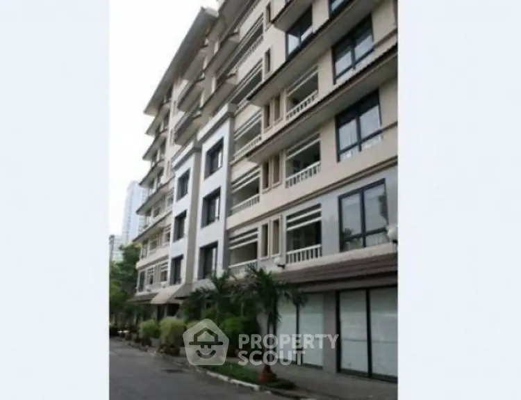 Elegant multi-story residential building with balconies and lush greenery.