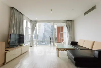 Spacious modern living room with large windows and city view, featuring sleek furniture and natural light.