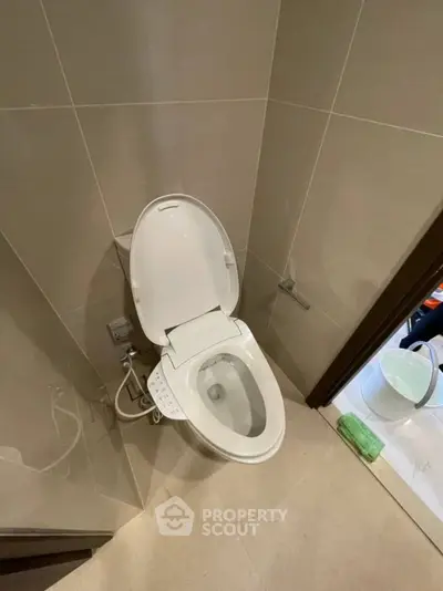 Modern bathroom with sleek toilet and tiled walls, showcasing contemporary design and functionality.