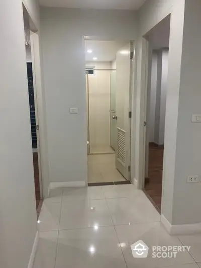 Modern apartment hallway with glossy tiled flooring and neutral walls