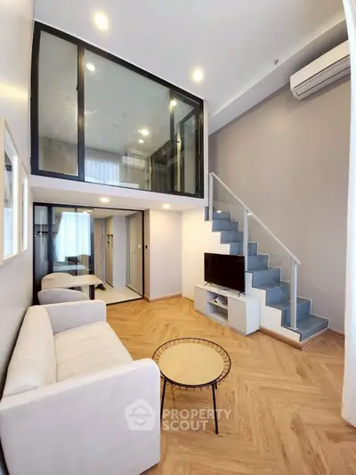Modern loft-style living room with mezzanine, sleek staircase, and cozy seating area.