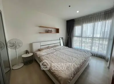 Spacious bedroom with large window and modern decor in a bright apartment.
