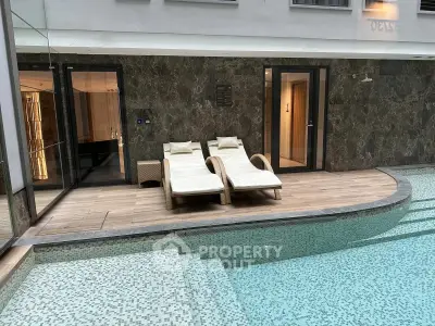Luxurious indoor pool area with stylish lounge chairs and modern design.