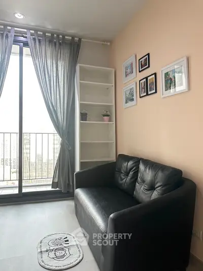 Cozy living room with black leather sofa, wall art, and balcony view in modern apartment.