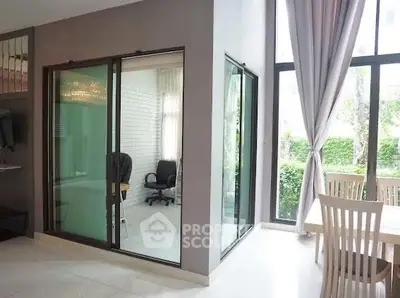 Modern living room with glass-enclosed study area and large windows for natural light.