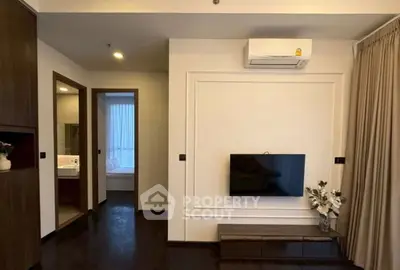Modern living room with wall-mounted TV and air conditioning, featuring elegant decor and dark wood flooring.
