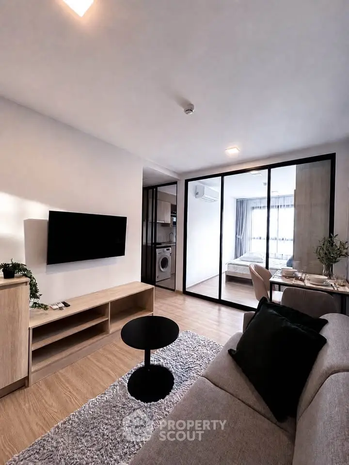 Modern living room with sleek design and glass partition leading to bedroom