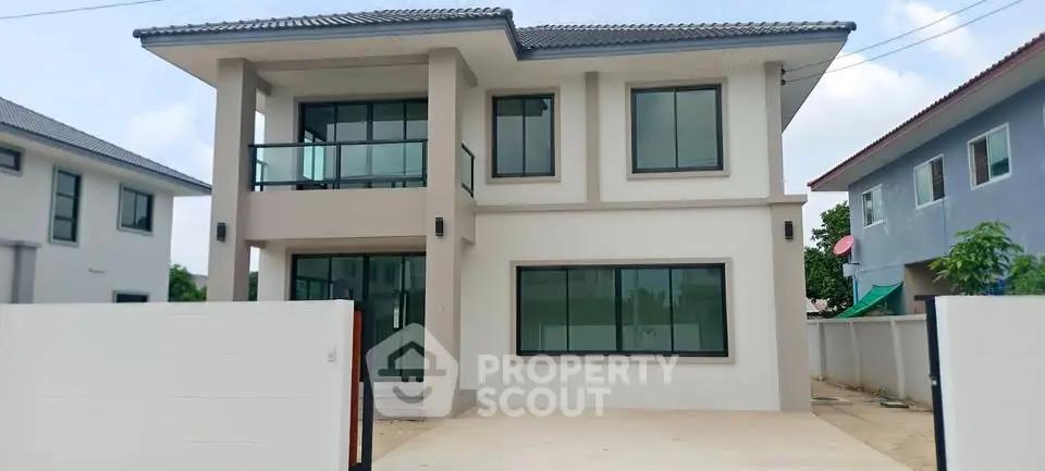 Modern two-story house with large windows and sleek design in a suburban neighborhood.