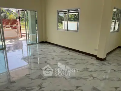 Spacious living room with marble flooring and large windows opening to a patio.