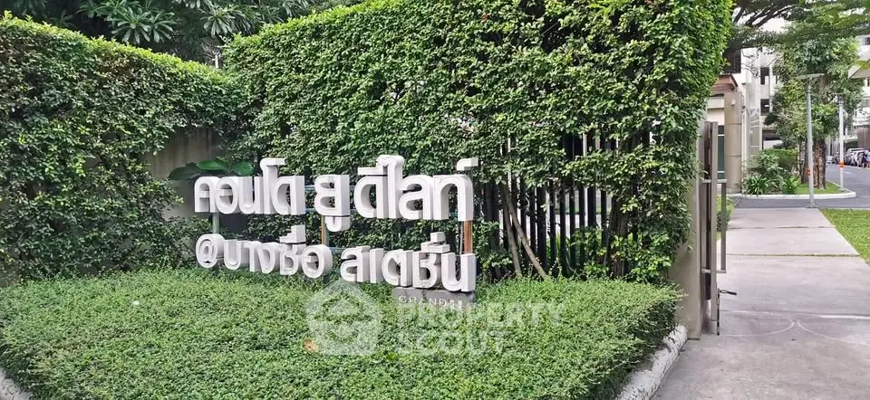 Modern condo entrance with lush greenery and stylish signage