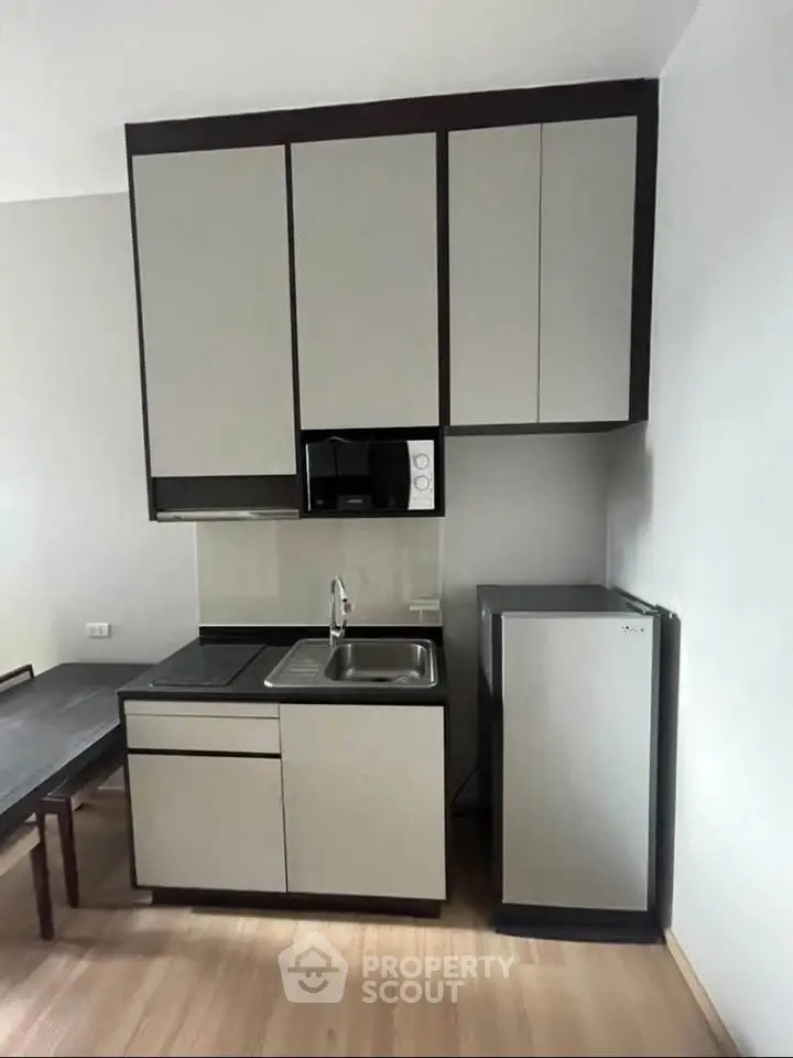 Modern compact kitchen with sleek cabinetry and mini fridge