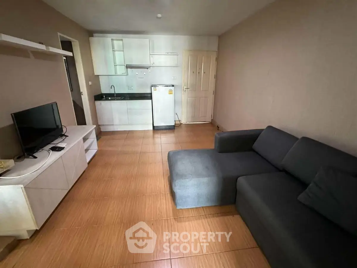 Modern living room with sleek furniture and compact kitchen area.