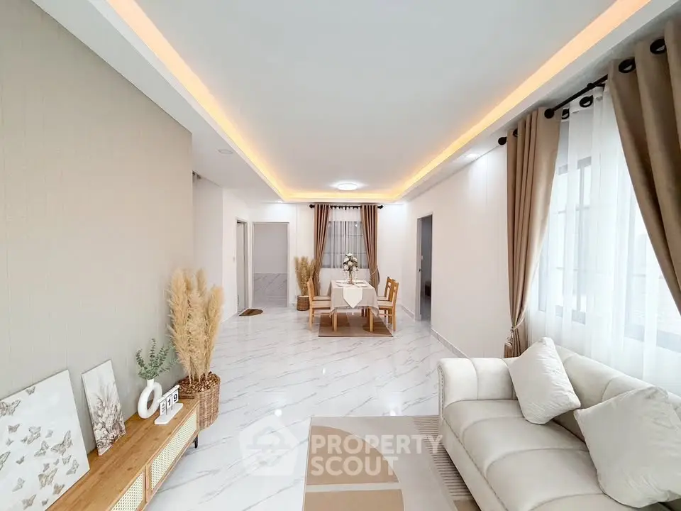 Elegant living room with modern decor and dining area, featuring soft lighting and stylish furnishings.