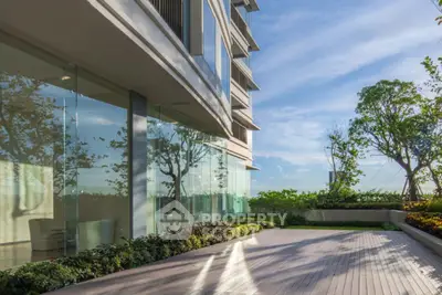 Modern building exterior with glass facade and spacious wooden deck surrounded by lush greenery.