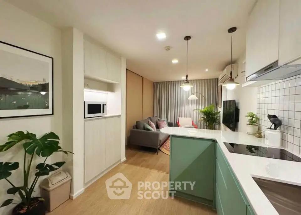 Modern open-layout kitchen and living room with stylish decor and ample lighting.