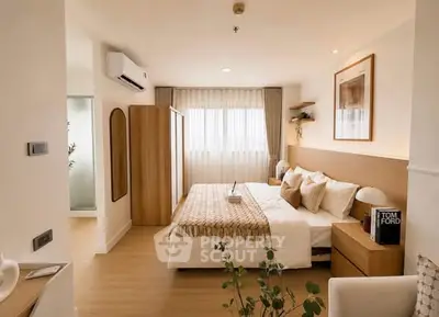 Modern bedroom with stylish decor and natural light, featuring a cozy bed and elegant furnishings.