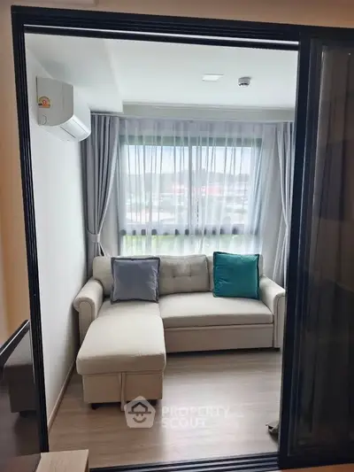 Cozy living room with modern sofa and large window offering natural light.
