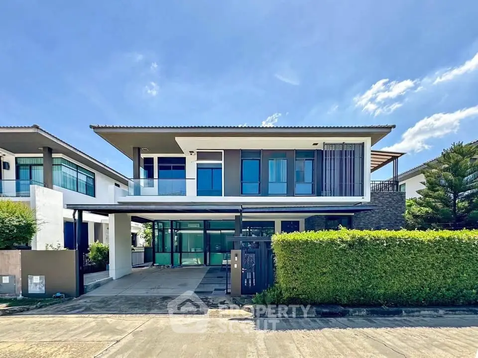 Modern two-story house with large windows and spacious driveway in a serene neighborhood.