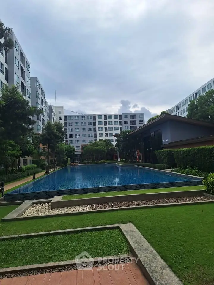 Modern apartment complex with lush greenery and inviting swimming pool