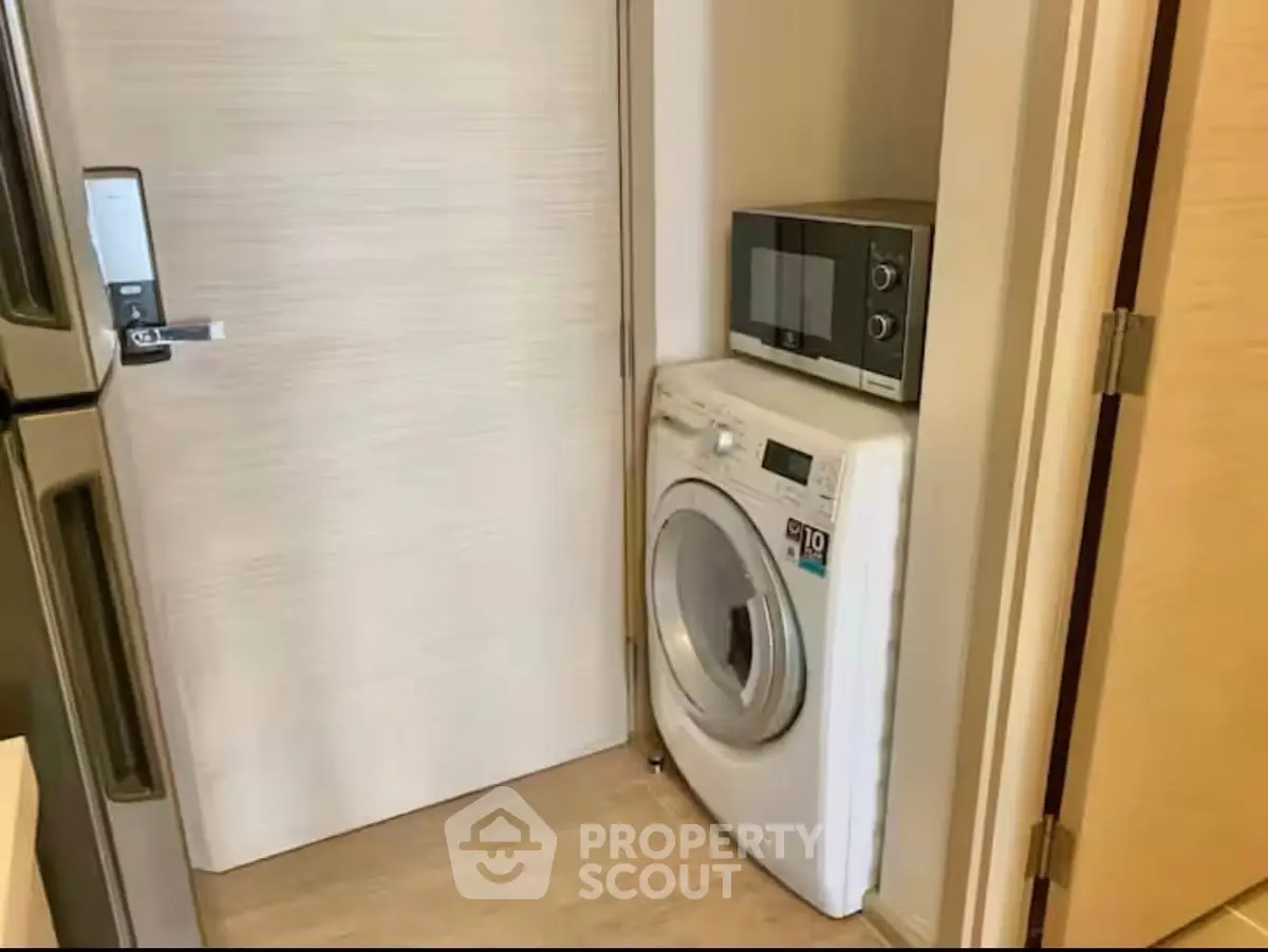 Compact laundry area with washing machine and microwave in modern home.