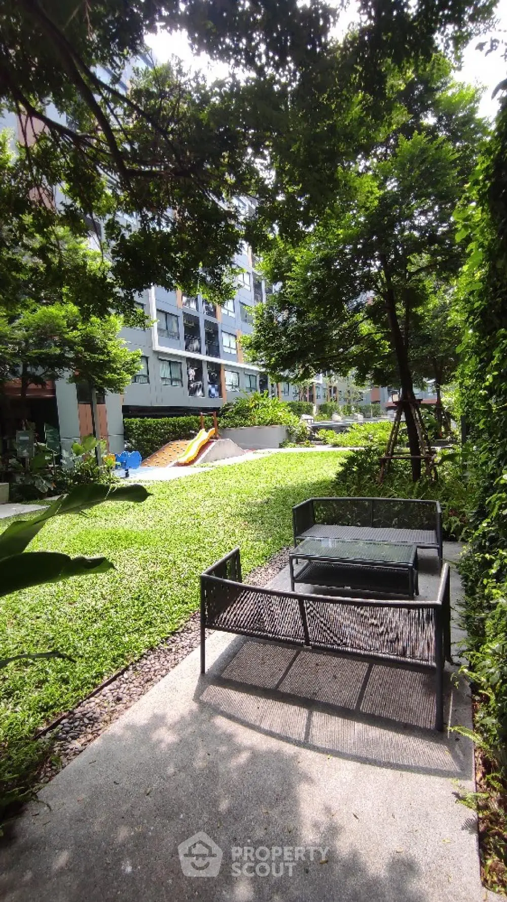 Lush garden area with seating and playground in modern residential complex