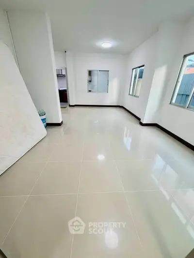 Spacious unfurnished room with glossy tiled flooring and large windows for natural light.