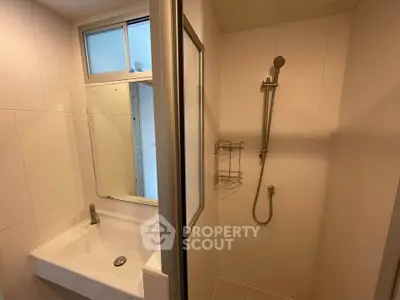 Compact bathroom with modern shower and sink in minimalist design.