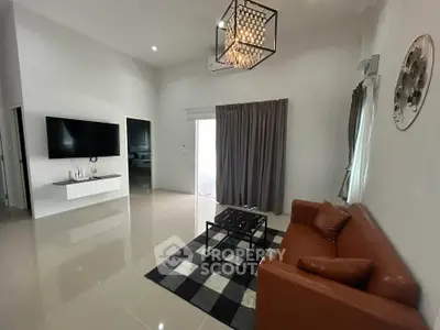 Modern living room with sleek design, featuring a leather sofa, wall-mounted TV, and elegant chandelier.