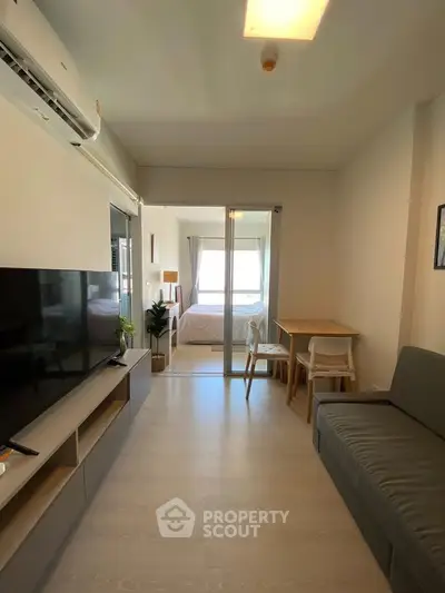 Modern apartment interior with cozy living room and bedroom view, featuring sleek furniture and natural light.