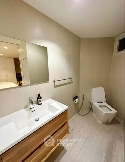 Modern bathroom with sleek fixtures and minimalist design, featuring a spacious vanity and contemporary toilet.