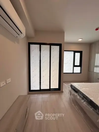 Modern bedroom with large windows and air conditioning, featuring sleek design and natural light.