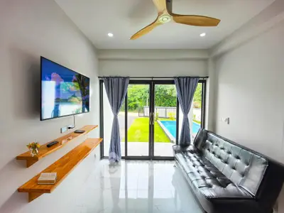 Modern living room with pool view, sleek leather sofa, and wall-mounted TV.