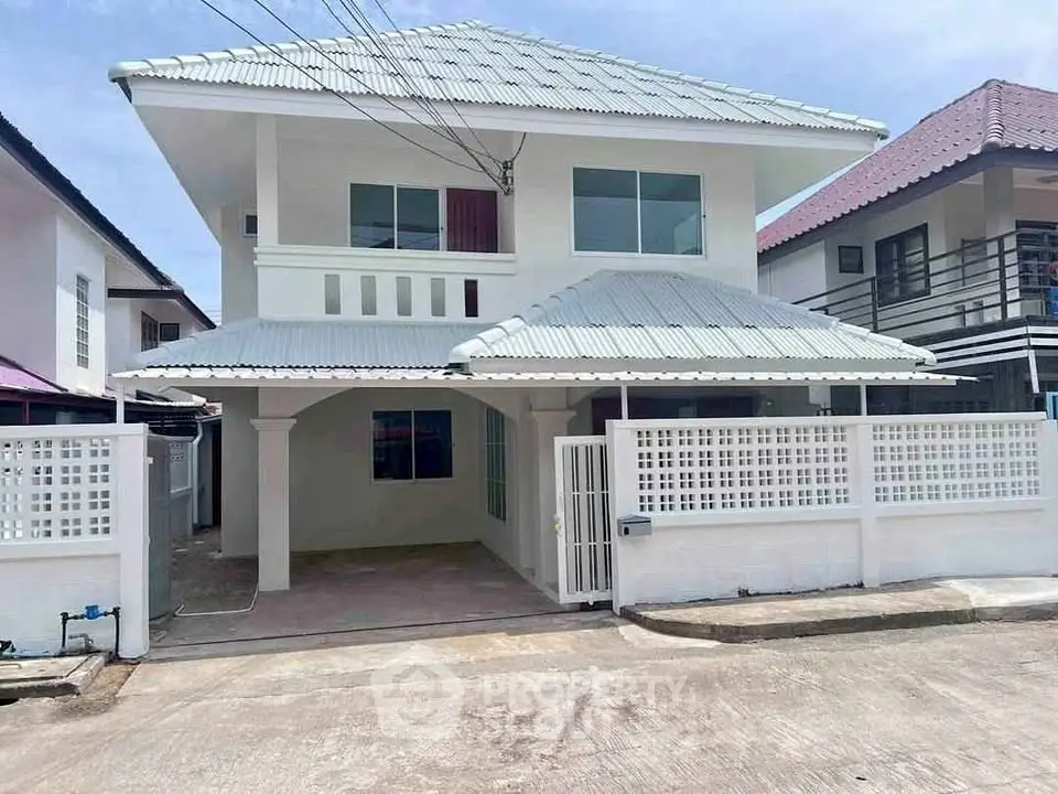 Charming two-story white house with gated driveway and modern roof design.