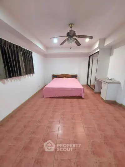 Spacious bedroom with terracotta tiled flooring, ceiling fan, and large wardrobe, offering a blank canvas for personalization.