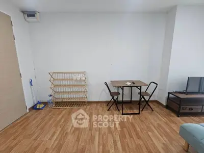 Minimalist living room with wooden flooring, small dining table, and TV stand.