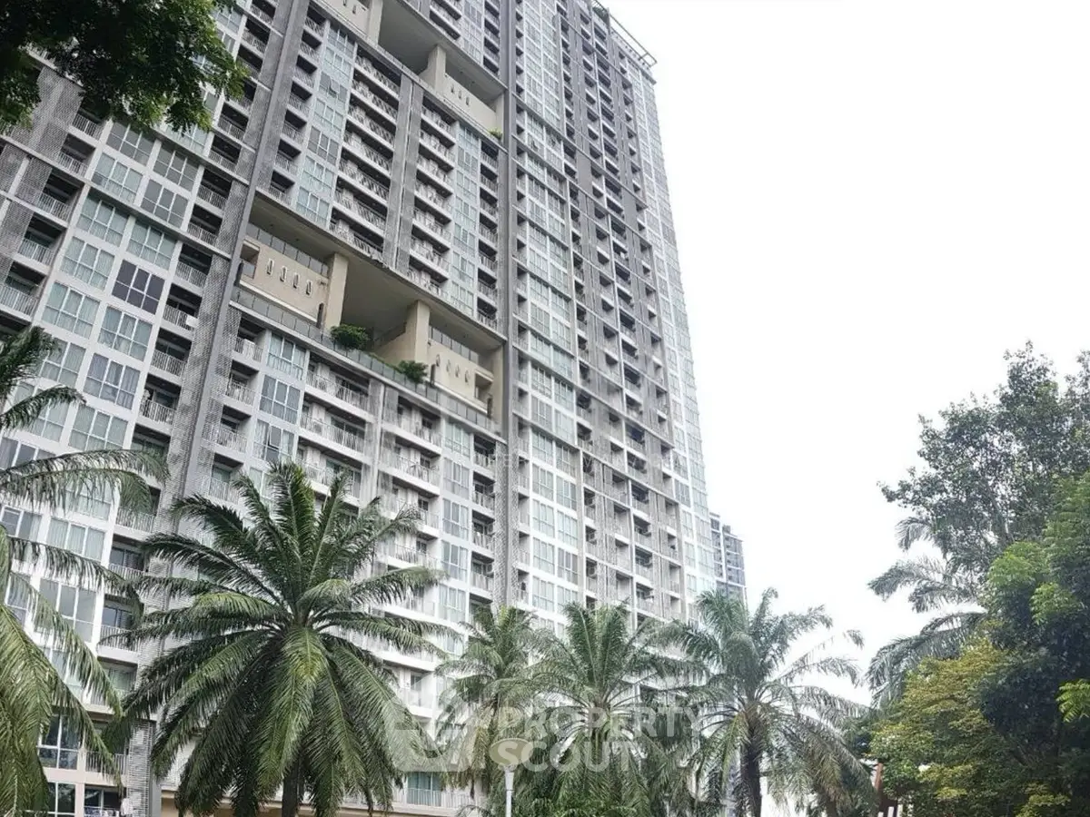 Modern high-rise building with lush palm trees and spacious balconies.