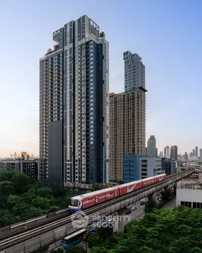 Modern high-rise buildings with train and lush greenery in urban setting.