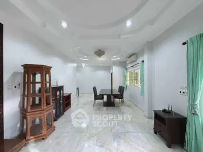Spacious living room with elegant decor and natural light, featuring a dining area and stylish furnishings.