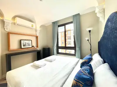 Elegant bedroom with large window and stylish decor, featuring a comfortable bed and modern lighting.