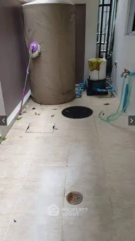 Spacious utility area with water tank and tiled flooring, ideal for storage or laundry setup.