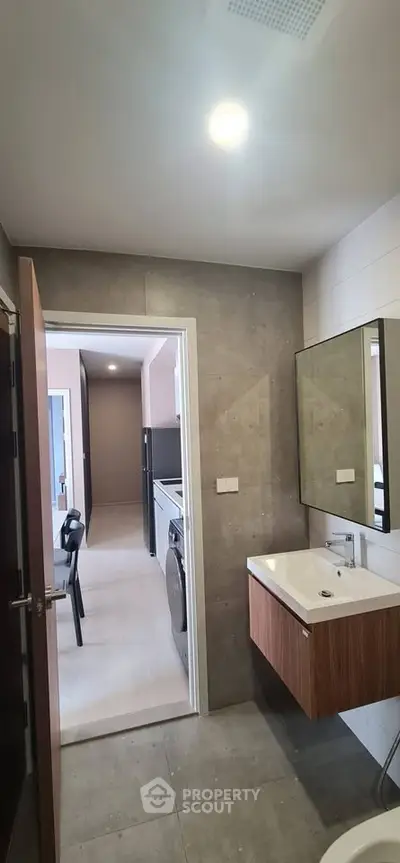 Modern bathroom with sleek fixtures and view into a stylish hallway with appliances.