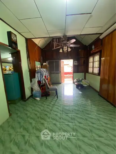 Charming vintage interior with wooden walls and green tiled floor, featuring a ceiling fan and cozy atmosphere.