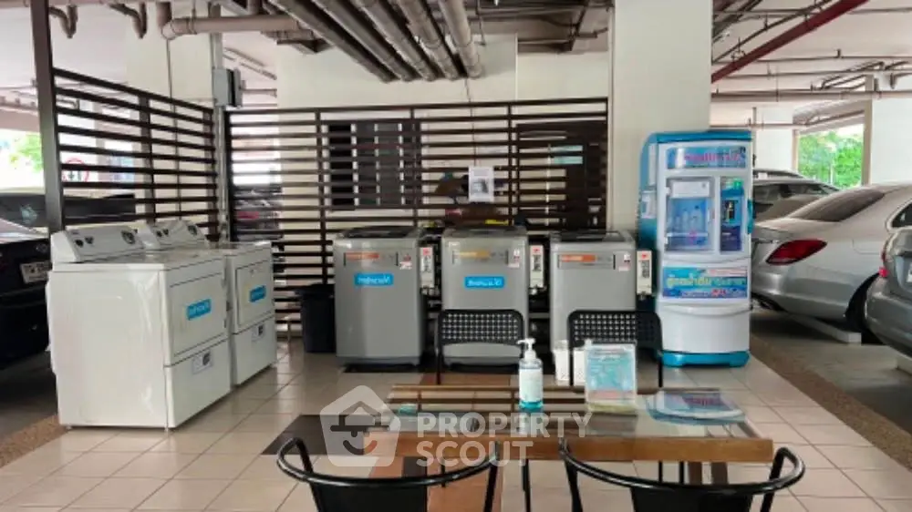Modern shared laundry area in residential building with washing machines and seating.