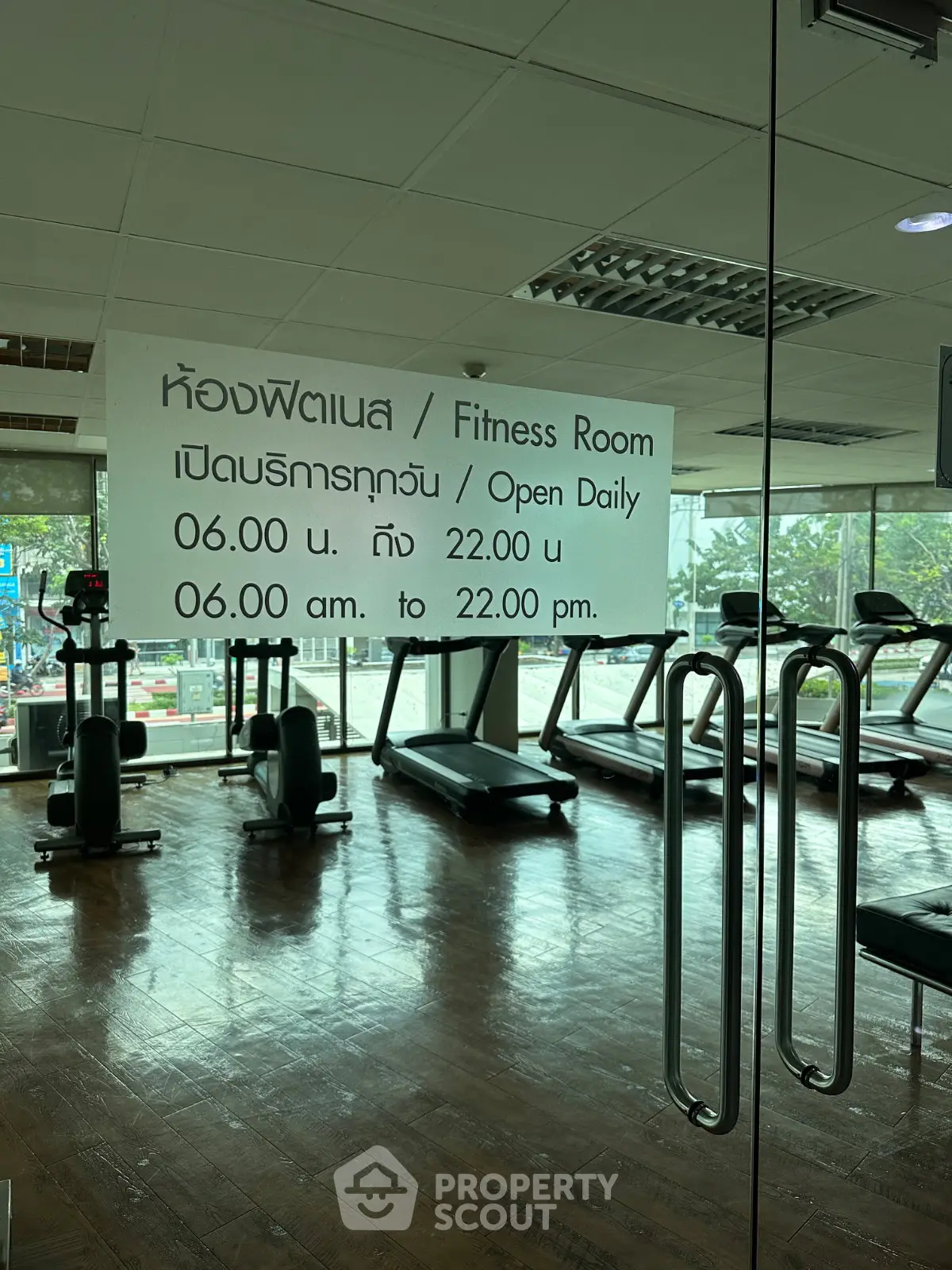 Modern fitness room with treadmills and large windows in a real estate property.