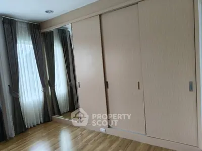 Spacious bedroom with elegant wooden wardrobe and large windows with curtains